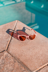 Pink pearl woman&rsquo;s sunglasses on pool deck poolside