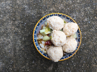 A close-up photo of hands holding delicious meatballs on a white bowl. Bakso is a very popular food in Indonesia, that made from ground beef or chicken meat mixed with tapioca flour.