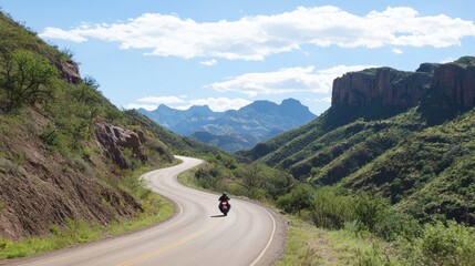 Riding through Nature's Majesty: Motorcyclist on Scenic Mountain Pass with Winding Road View