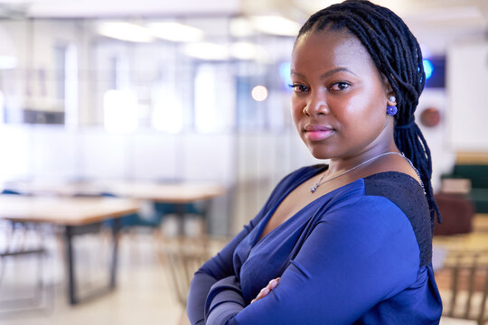Positive, charming, confident natural African American woman standing in trendy office wearing fashionable clothing