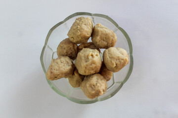 Top view of small meatballs in a glass bowl, isolated on white background