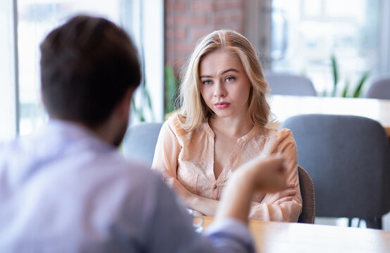 Bad date. Young woman feeling bored during dinner at cafe, unhappy with her boyfriend, disinterested in conversation. Stressed couple having difficulties in relationship, arguing in coffee shop