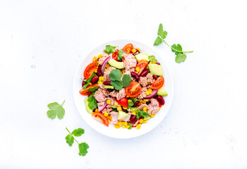 Mexican style salad with tuna, avocado, corn, beans, tomatoes and cilantro, white background, top view