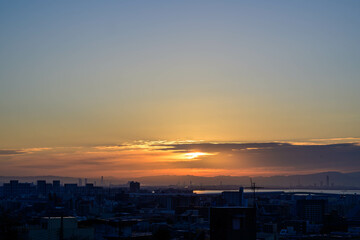 都市の夜明け。冬の朝神戸岡本の高台、梅林公園から市街地と大阪湾から日が昇る