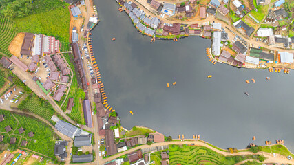 aerial top view of a lakeside village, showcasing a mix of rustic architecture, lush greenery, and...