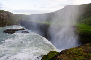 Gullfoss Waterfall, part of Iceland's golden circle route shimmers in deep blue as the icy water plunges into the gorge under dramatic skies 