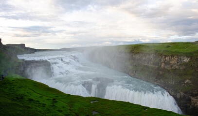 Gullfoss Waterfall, part of Iceland's golden circle route shimmers in deep blue as the icy water plunges into the gorge under dramatic skies 