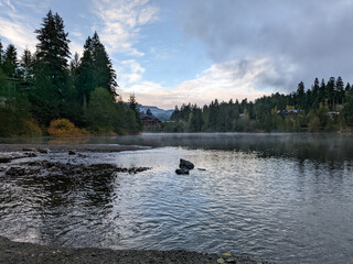 Chilly Alta Lake in Whistler BC Canada reflecting pine trees and mountains in the water with dramatic clouds and skies