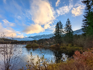 Snow covered Whistler mountain and the nearby peaks of Garibaldi park are seen in the background with a crisp lake in the foreground in BC Canada