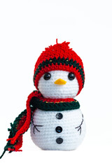 A small crocheted snowman wearing a red hat and a green and red scarf