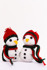 Two snowmen with red hats and scarves are sitting next to each other