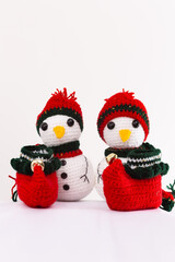 Three snowmen with red hats and scarves are sitting on a white table