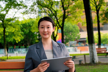 Fototapeta premium Professional Woman Engaged with Tablet in Lush Park Setting