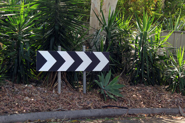 Turn right road sign in a garden with trees