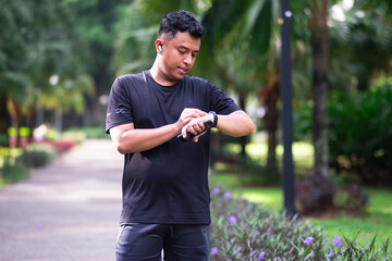 Asian Runner with fitness smart watch, app and check running time for health tracking tech on nature run. Sports athlete doing workout practice for cardio wellness, physical fitness