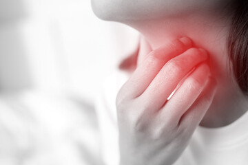 sore throat pain. Closeup of young woman sick holding her inflamed throat using hands to touch the ill neck in blue shirt on gray background. Medical and healthcare concept.