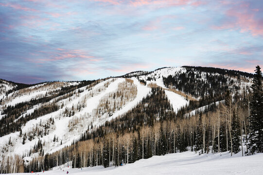 Steamboat Colorado ski slopes are blanketed in snow, basking under a crisp morning sky painted in soft blue and pink hues.