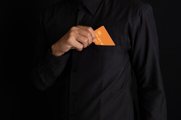 Hand holding credit card and laptop or digital tablet on black background. New online transaction concept to meet needs and desires.