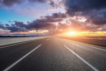 Naklejka premium Straight highway road and coastline with beautiful sky clouds nature landscape at sunset. Outdoor road background.