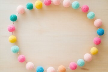 Obraz premium Pastel-colored pom-pom garland forms a circle on a light wooden background.