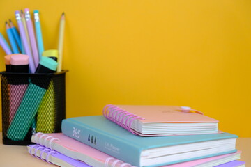 Top view of an assortment of school supplies on a vibrant yellow background. this image features colorful pencils, notebooks, scissors, erasers, and paper clips, back to school concept with text space