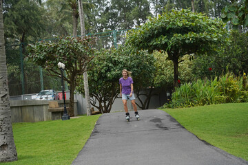 A woman is rollerblading gracefully on a road located in a park