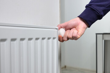 A man opens a valve on a heating radiator in an apartment or house. The beginning of the cold season.