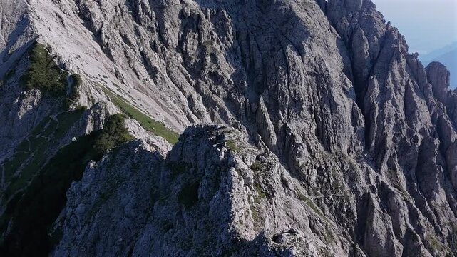 Drone flying over rocky mountain peak, summer season, sunlight, Grignetta, Alps, Italy, Aerial orbiting