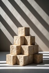 Stacked stone cubes with dramatic shadows in artistic indoor setting during daylight