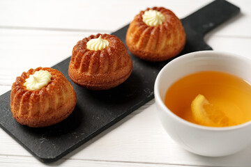 Delicious miniature bundt cakes served with tea and lemon slice on a wooden table