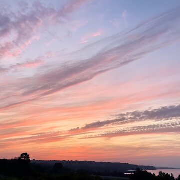 Vibrant sunset sky with wispy clouds over rolling hills at dusk