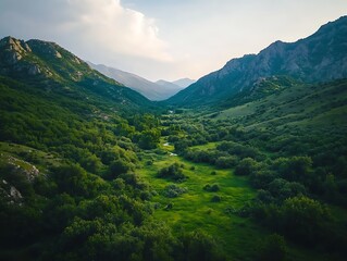 Naklejka premium Drone shot of a green valley surrounded by steep, rocky mountains 