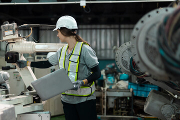 Robotic engineer women automatic mechanic using laptop checking quality system of automation robot arms machine in factory. Service programming machinery welding robots in production at factory.