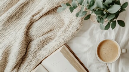 Flat lay of a cozy autumn scene with a warm drink, blanket, and book for a lifestyle or coffee brand ad