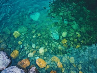 Fototapeta premium Top-down perspective of a crystal-clear alpine lake with visible rocks 