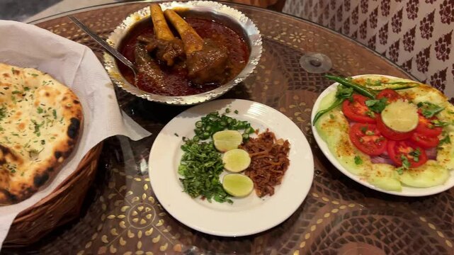 Indian cuisine consisting of Nalli Nihari, naan and salad served in restaurant.