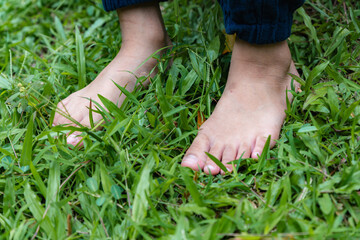 walking in a green fresh grass meadow, barefoot