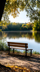 Obraz premium Autumnal park bench by lake, peaceful scene, fall foliage, city background, relaxation.