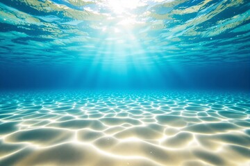 Obraz premium Sunlight breaking through ocean waves illuminating sandy seabed in vibrant blue tones.