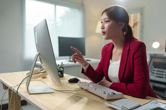 Young professional engaging in an online meeting, discussing project details with colleagues while seated at a desk in a modern office environment, utilizing technology for effective communication