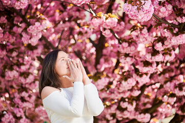 Woman allergic suffering from seasonal allergy at spring in blossoming garden at springtime. Young...