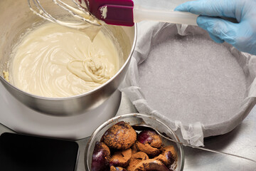 Everything is ready for baking plum pie: a form with parchment, dough in a mixer and plums