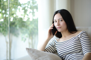 Serious asian woman talking on phone looking at you