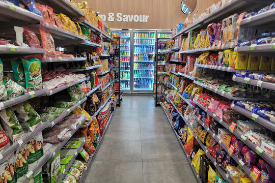 Penang, Malaysia - Nov 23, 2024: Interior view of a 7-Eleven convenience store featuring snack and beverage aisles, showcasing a wide variety of packaged products and refrigerated drinks.