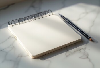 Spiral notebook and pens on white desk with soft light.