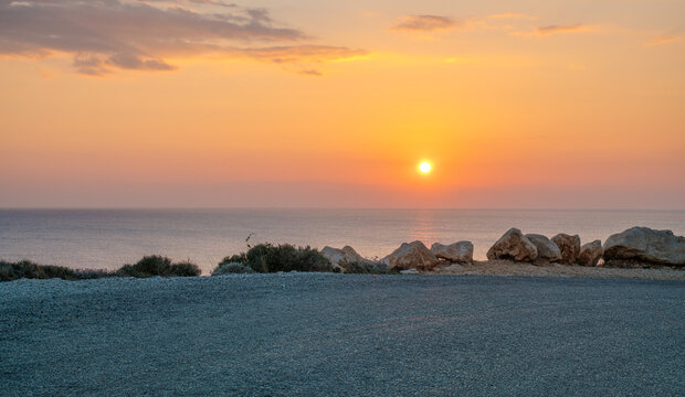 A bend in the paved road on a seaside cliff during sunset