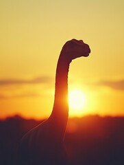 Silhouette of a dinosaur against a vibrant sunset backdrop.