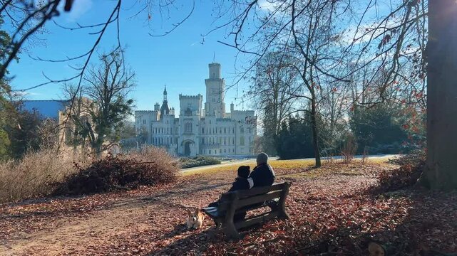 Father and son relax on a bench at Hluboka nad Vltavou castle in Czech