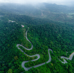 Aerial drone view of winding mountain road surrounded with greenery rainforest at Wang Kelian, Perlis, Malaysia.