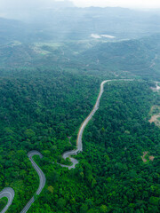 Aerial drone view of winding mountain road surrounded with greenery rainforest at Wang Kelian, Perlis, Malaysia.